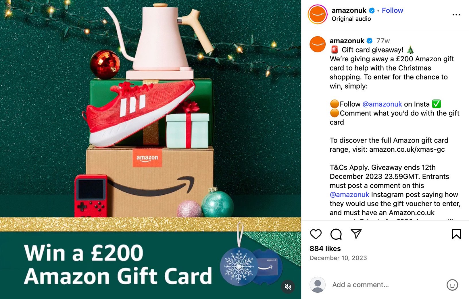 Amazon package and gift boxes topped with a red sneaker and kettle in front of festive lights