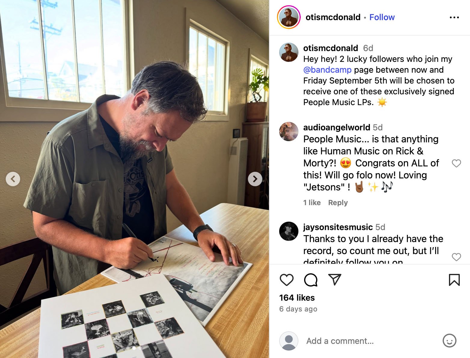 Musician signing vinyl record sleeves at a table for a Bandcamp giveaway promotion
