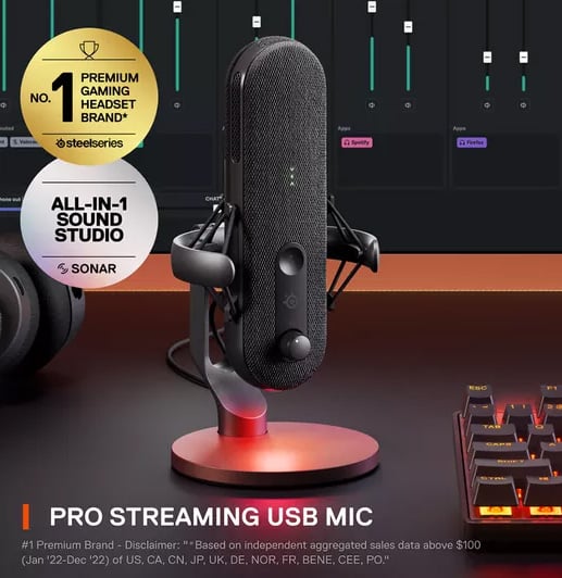 SteelSeries Alias USB microphone set up on a streamer’s desk with headset, RGB keyboard, and software interface in background