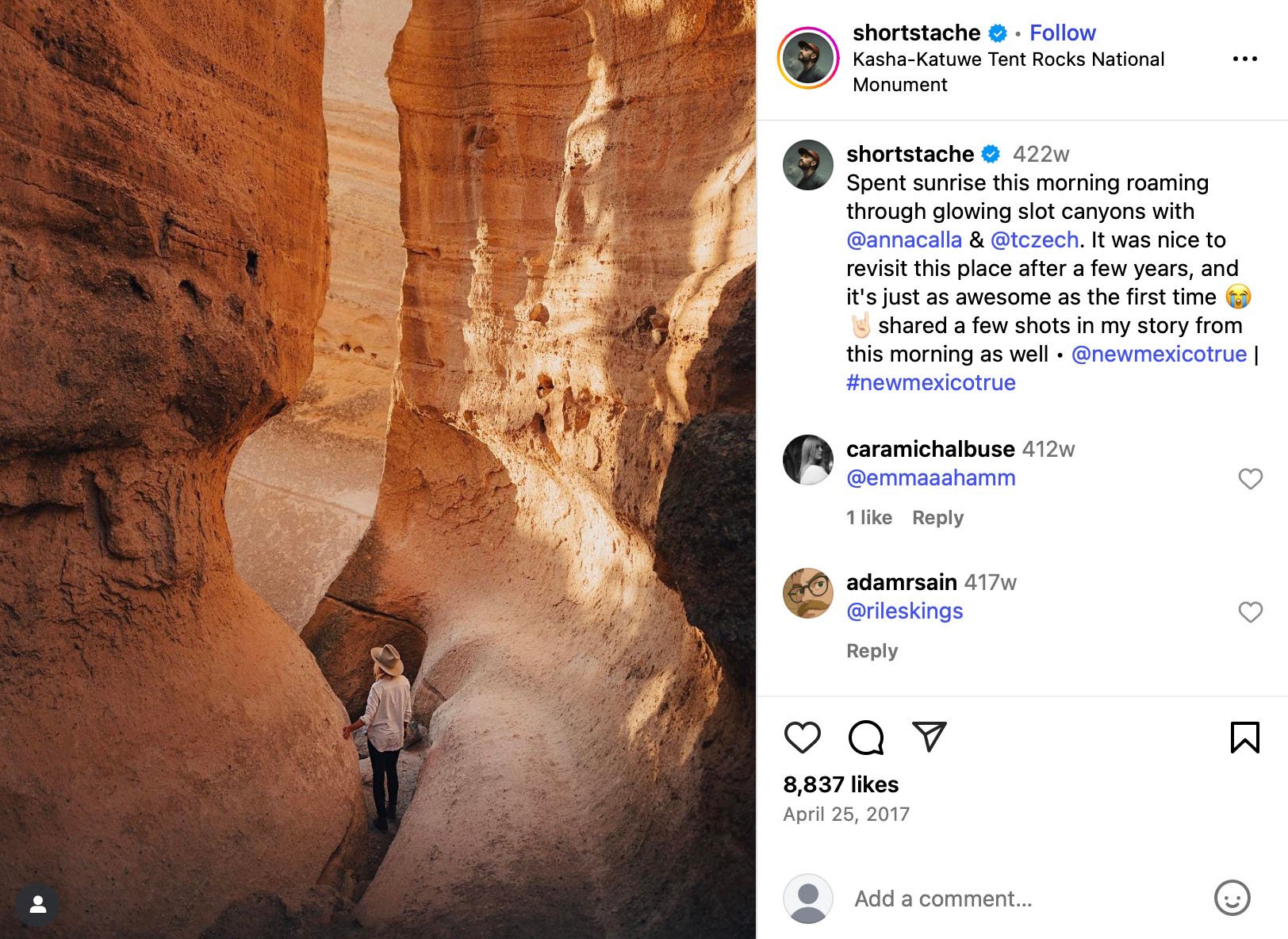 Person wearing a hat walking through red rock slot canyon at sunrise